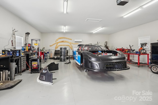 garage with a garage door opener, a wall unit AC, and a workshop area