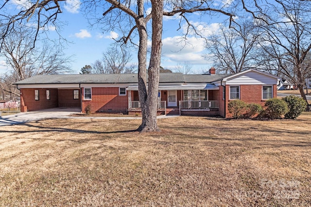 back of house with a carport, covered porch, and a lawn