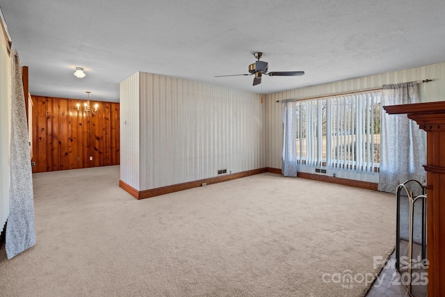 unfurnished living room featuring carpet flooring, ceiling fan with notable chandelier, and a textured ceiling