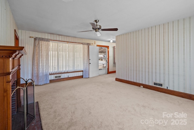 unfurnished living room with ceiling fan and carpet