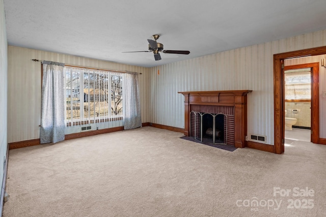 unfurnished living room featuring a fireplace, carpet floors, and ceiling fan