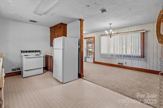 kitchen featuring pendant lighting, white appliances, a textured ceiling, and a chandelier