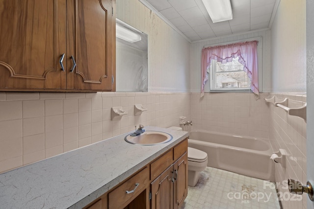 bathroom with tile walls, a bathtub, vanity, ornamental molding, and toilet