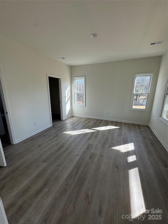 spare room featuring dark hardwood / wood-style floors and a healthy amount of sunlight