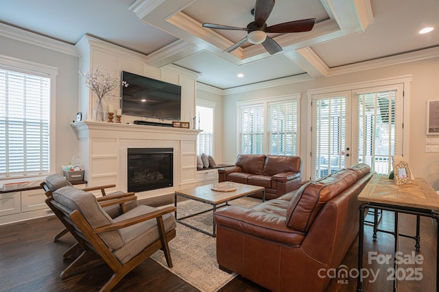 living room featuring a tile fireplace, ornamental molding, dark hardwood / wood-style floors, and french doors