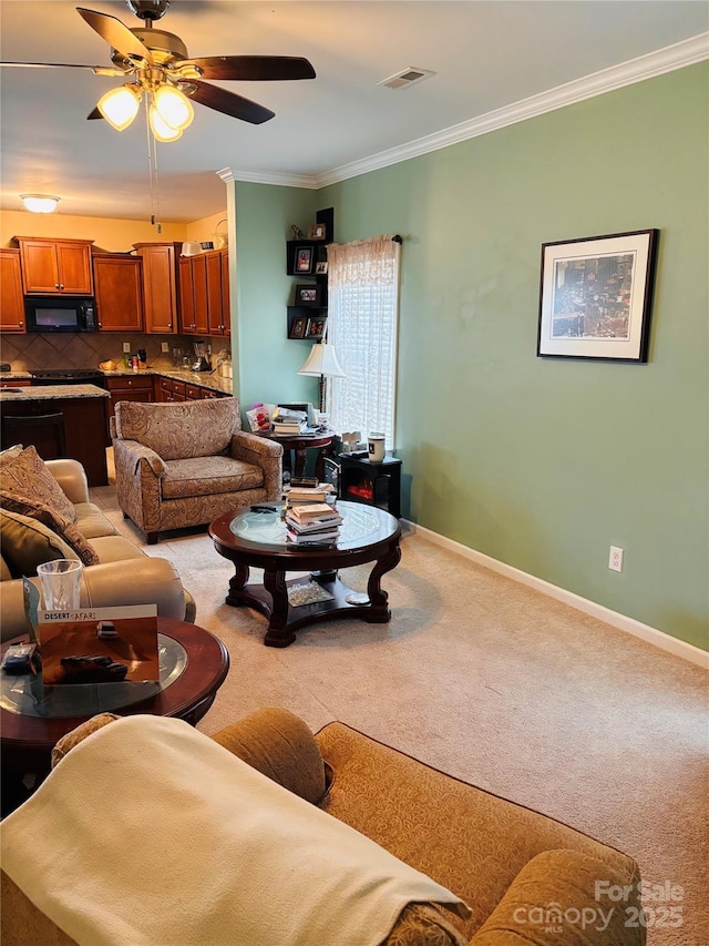 carpeted living room featuring ornamental molding and ceiling fan