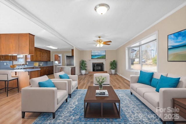 living room with ornamental molding, ceiling fan, and light wood-type flooring