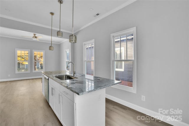 kitchen with stone countertops, sink, hanging light fixtures, white cabinets, and a center island with sink