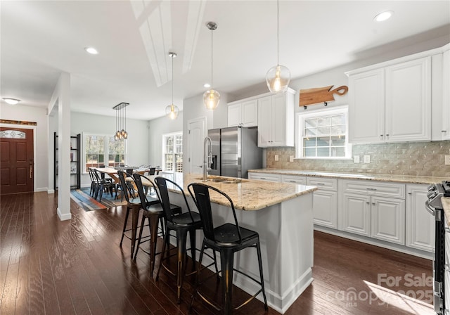 kitchen with pendant lighting, an island with sink, white cabinets, and appliances with stainless steel finishes