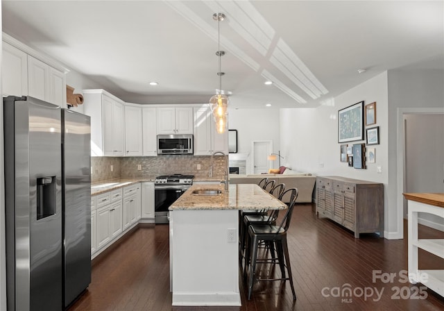 kitchen with sink, white cabinetry, appliances with stainless steel finishes, an island with sink, and light stone countertops