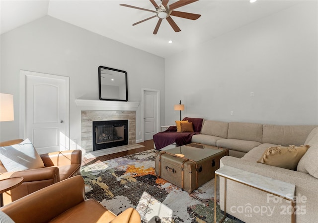 living room featuring hardwood / wood-style flooring, ceiling fan, vaulted ceiling, and a tile fireplace