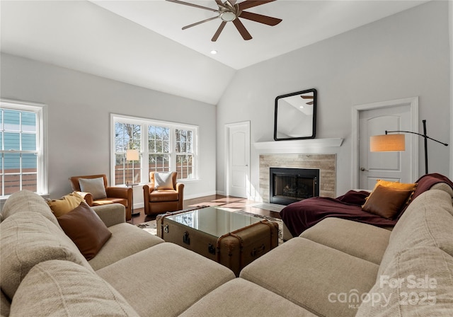 living room featuring ceiling fan, wood-type flooring, a tiled fireplace, and vaulted ceiling