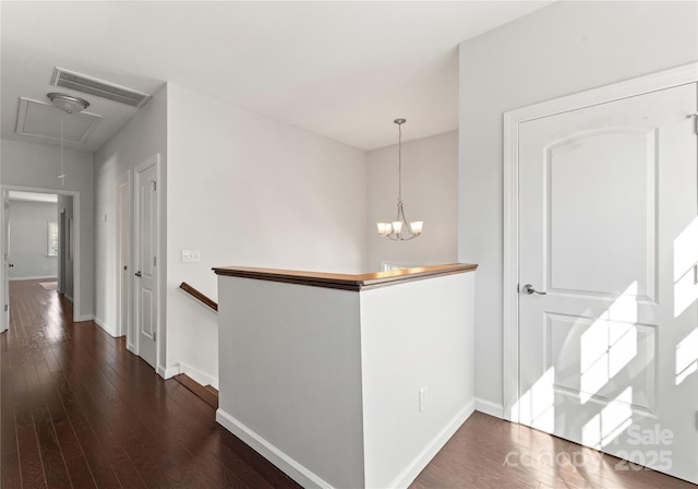 hallway with dark hardwood / wood-style flooring and an inviting chandelier