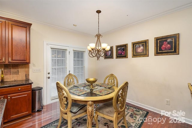 dining area featuring ornamental molding, a notable chandelier, and dark hardwood / wood-style flooring