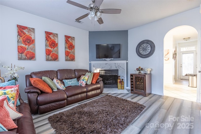 living room featuring ceiling fan, a fireplace, and light hardwood / wood-style floors