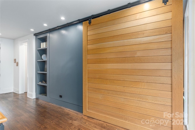 interior space featuring built in features, recessed lighting, a barn door, wood finished floors, and baseboards