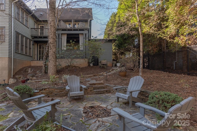 view of patio featuring fence and a balcony