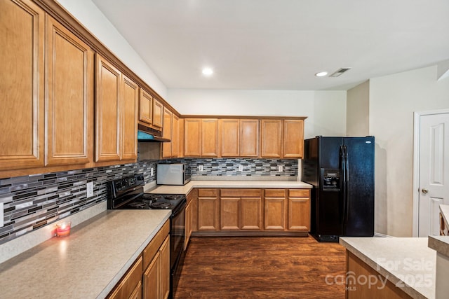 kitchen with dark hardwood / wood-style flooring, tasteful backsplash, and black appliances