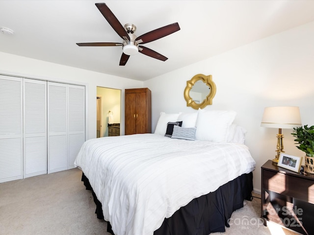 bedroom with light carpet, a closet, ceiling fan, and ensuite bathroom