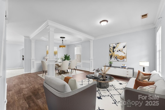 living room featuring hardwood / wood-style flooring, crown molding, and decorative columns