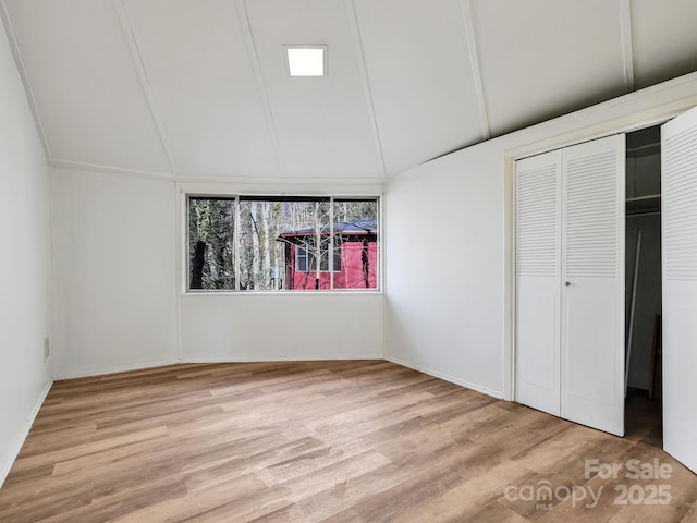 unfurnished bedroom with lofted ceiling, light hardwood / wood-style floors, and a closet