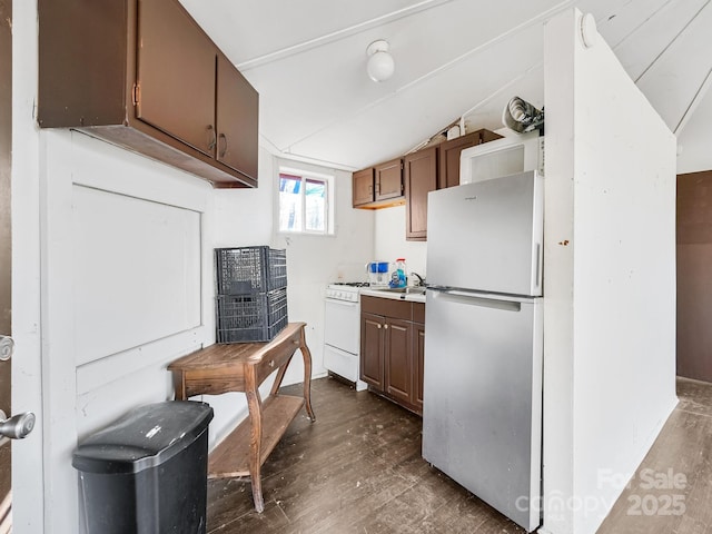 kitchen featuring lofted ceiling, sink, dark wood-type flooring, stainless steel fridge, and white gas range oven