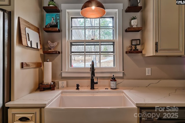 kitchen with light stone counters, sink, cream cabinets, and dishwasher