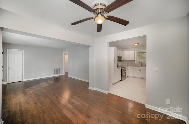 unfurnished living room with ceiling fan, sink, and light hardwood / wood-style floors