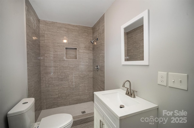 bathroom with vanity, toilet, and tiled shower