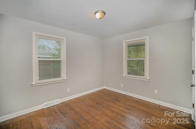 empty room with a healthy amount of sunlight and dark wood-type flooring