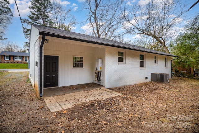 rear view of house featuring water heater and central AC unit