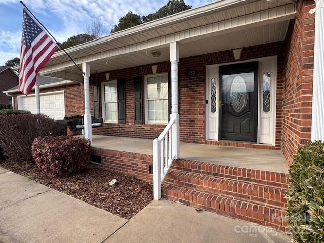 view of exterior entry featuring a garage and covered porch