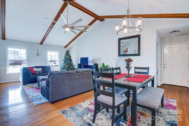 dining space with vaulted ceiling with beams, ceiling fan with notable chandelier, and light hardwood / wood-style floors