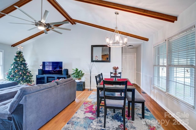 dining area with vaulted ceiling with beams, ceiling fan with notable chandelier, and light hardwood / wood-style floors