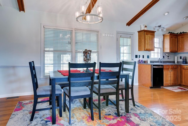 dining area with an inviting chandelier, sink, light hardwood / wood-style flooring, and beamed ceiling