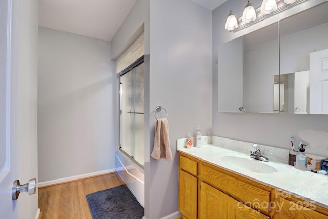 bathroom with vanity, hardwood / wood-style flooring, and bath / shower combo with glass door