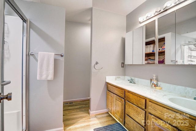 bathroom with hardwood / wood-style flooring, vanity, and a shower with shower door