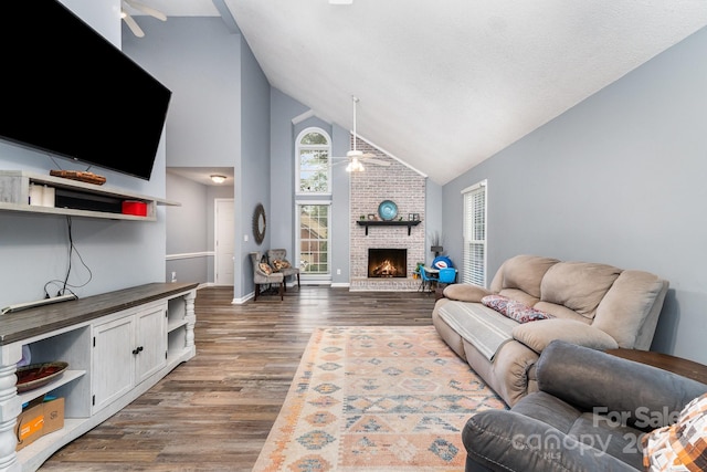living room with ceiling fan, high vaulted ceiling, dark wood-style flooring, a fireplace, and baseboards