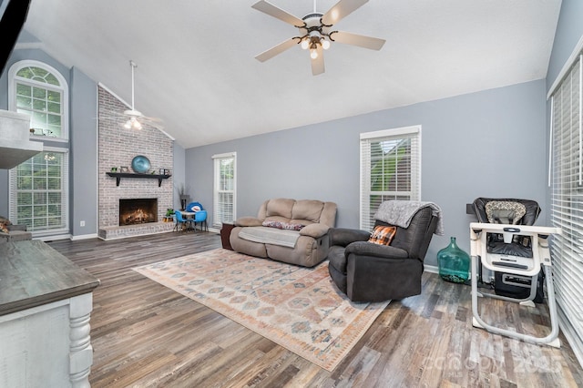 living room with ceiling fan, high vaulted ceiling, a brick fireplace, wood finished floors, and plenty of natural light