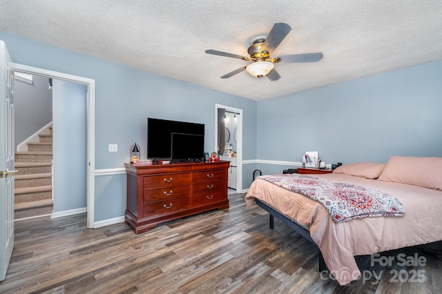 bedroom with wood finished floors, a textured ceiling, baseboards, and ceiling fan