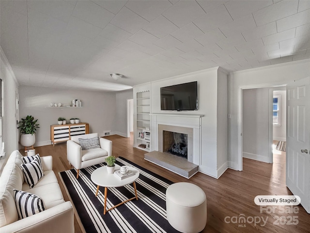 living room with crown molding, built in shelves, and wood-type flooring