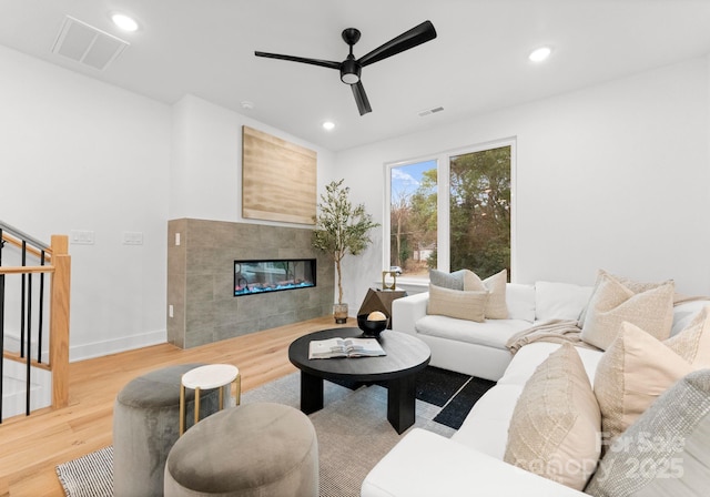 living room with a tile fireplace, hardwood / wood-style floors, and ceiling fan