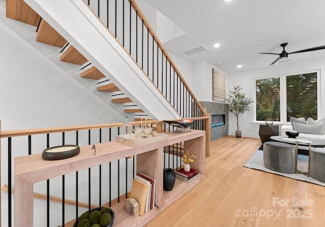 staircase with wood-type flooring and ceiling fan