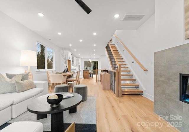 living room featuring a tile fireplace and light wood-type flooring