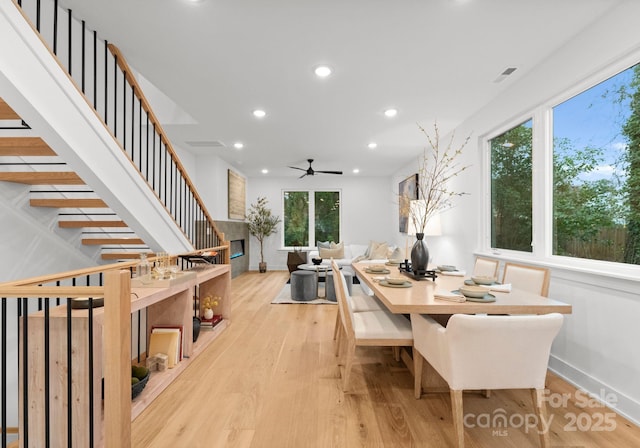 dining space featuring light hardwood / wood-style flooring, a large fireplace, and ceiling fan