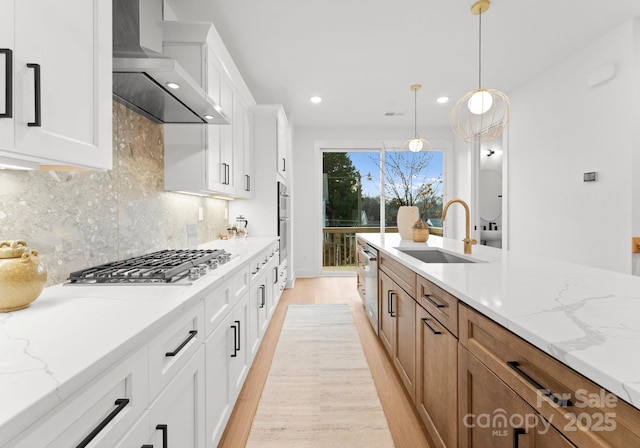 kitchen featuring white cabinetry, light stone counters, wall chimney exhaust hood, and appliances with stainless steel finishes