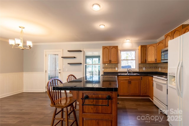 kitchen featuring a sink, white appliances, brown cabinetry, and wainscoting