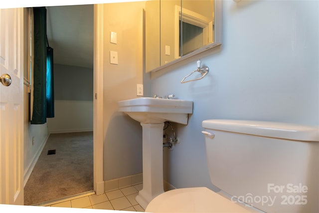 half bathroom with tile patterned flooring, toilet, and baseboards