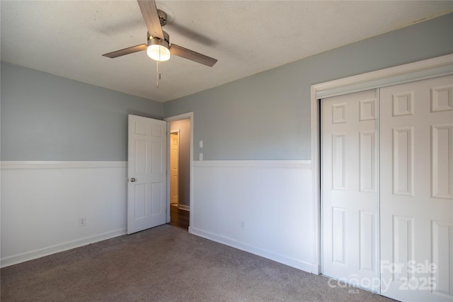 unfurnished bedroom with a closet, baseboards, ceiling fan, and carpet flooring