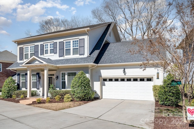 traditional home featuring concrete driveway, a shingled roof, and an attached garage